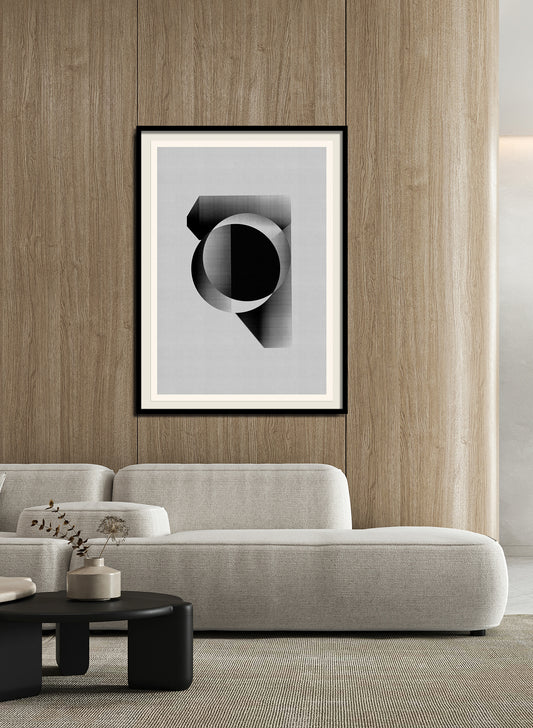 A modern living room with light wood panel walls, a curved light gray sofa, and a round black coffee table. "Abstract composition M432" (archival ink on cotton rag paper) is framed on the wall. Dried flowers rest on the table.