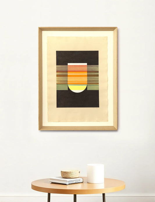 Framed abstract art piece on a white wall with a small table below.