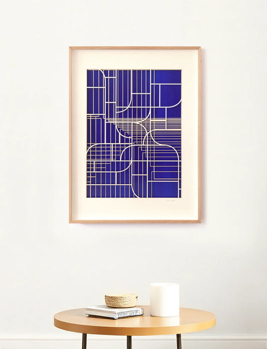 Mediterranean Window geometric artwork by Jesus Perea displayed on a white wall above a modern wooden side table with decorative interior objects.