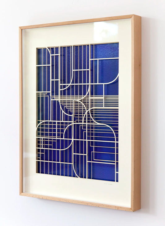 Oblique angled view of geometric abstract artwork by Jesús Perea, showing the overlapping laser-cut museum board layers that create a three-dimensional relief over the blue background.