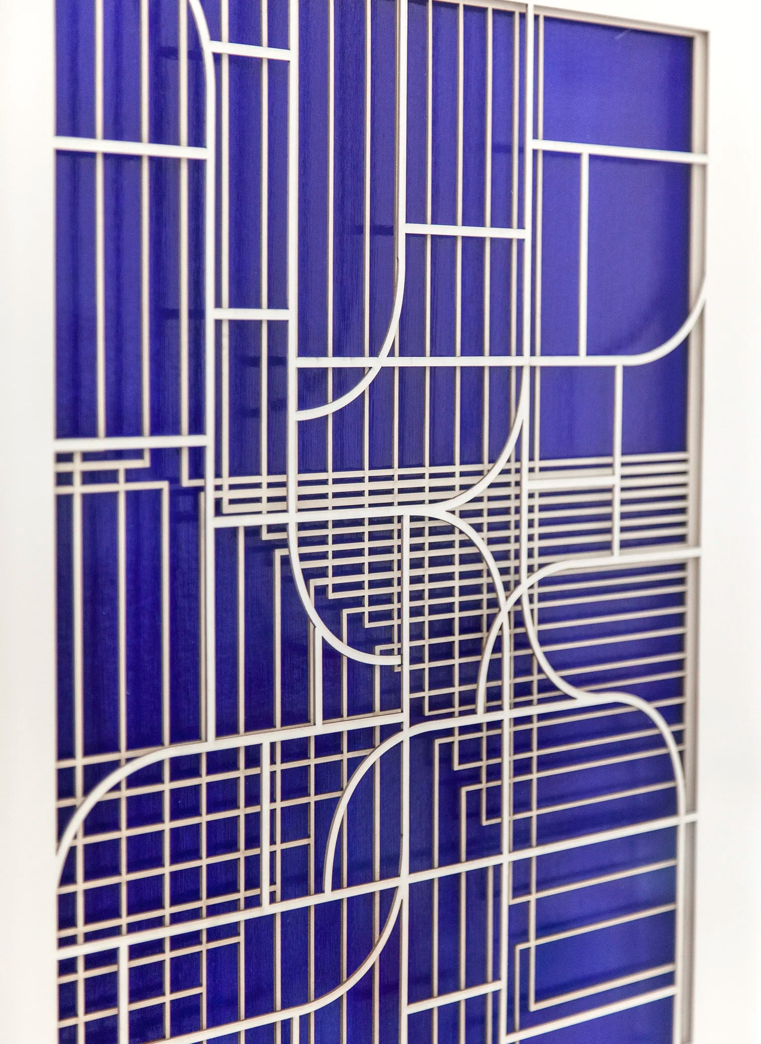 Close-up angled view of the geometric abstract artwork by Jesús Perea, focusing on the intricate laser-cut layers with a soft depth of field effect over the vibrant blue background.