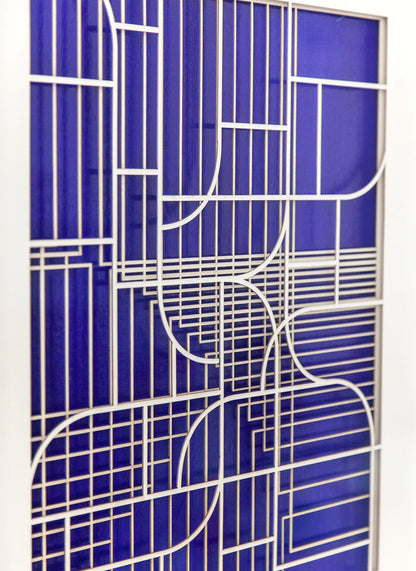 Close-up angled view of the geometric abstract artwork by Jesús Perea, focusing on the intricate laser-cut layers with a soft depth of field effect over the vibrant blue background.